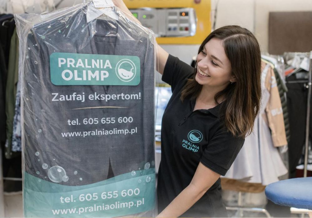 Pracownica Pralni Olimp wydaje odzież w firmowej folii